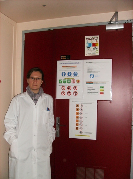 Marine Liotaud devant l'affiche des consignes de sécurité qu'elle a conçue et affichée sur la porte du laboratoire de Chimie qu'elle gère